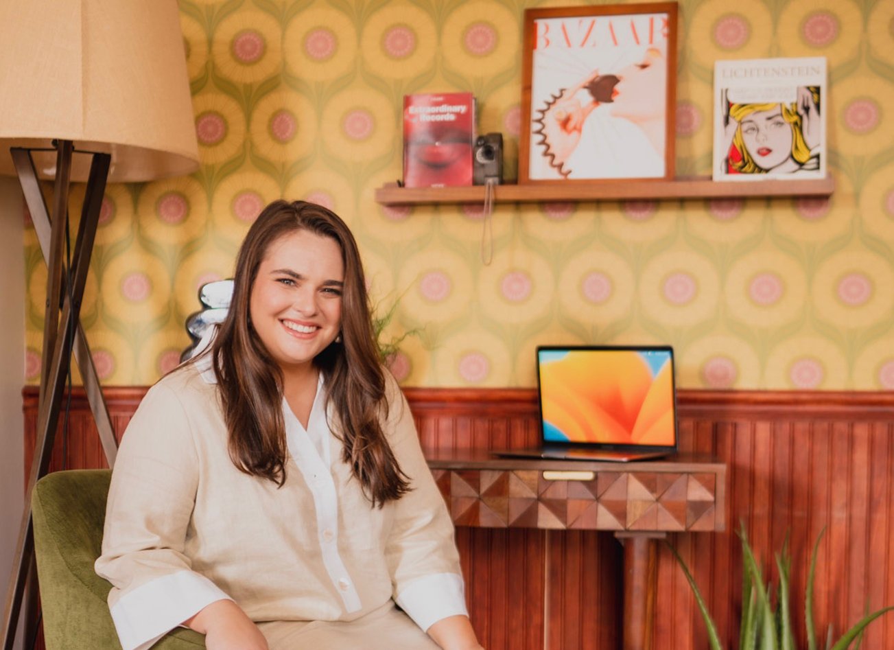 Andrea seated in a green chair beside a laptop
